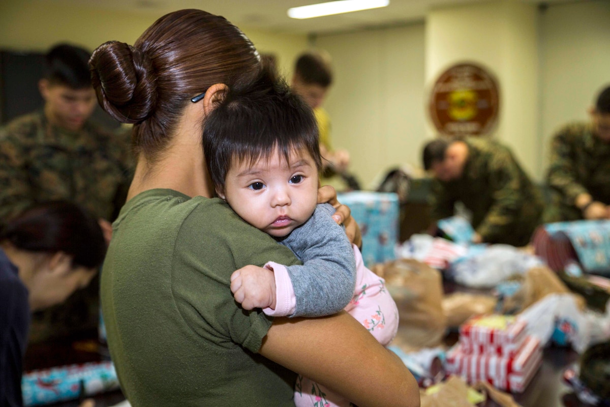 A Marine holds a young child.