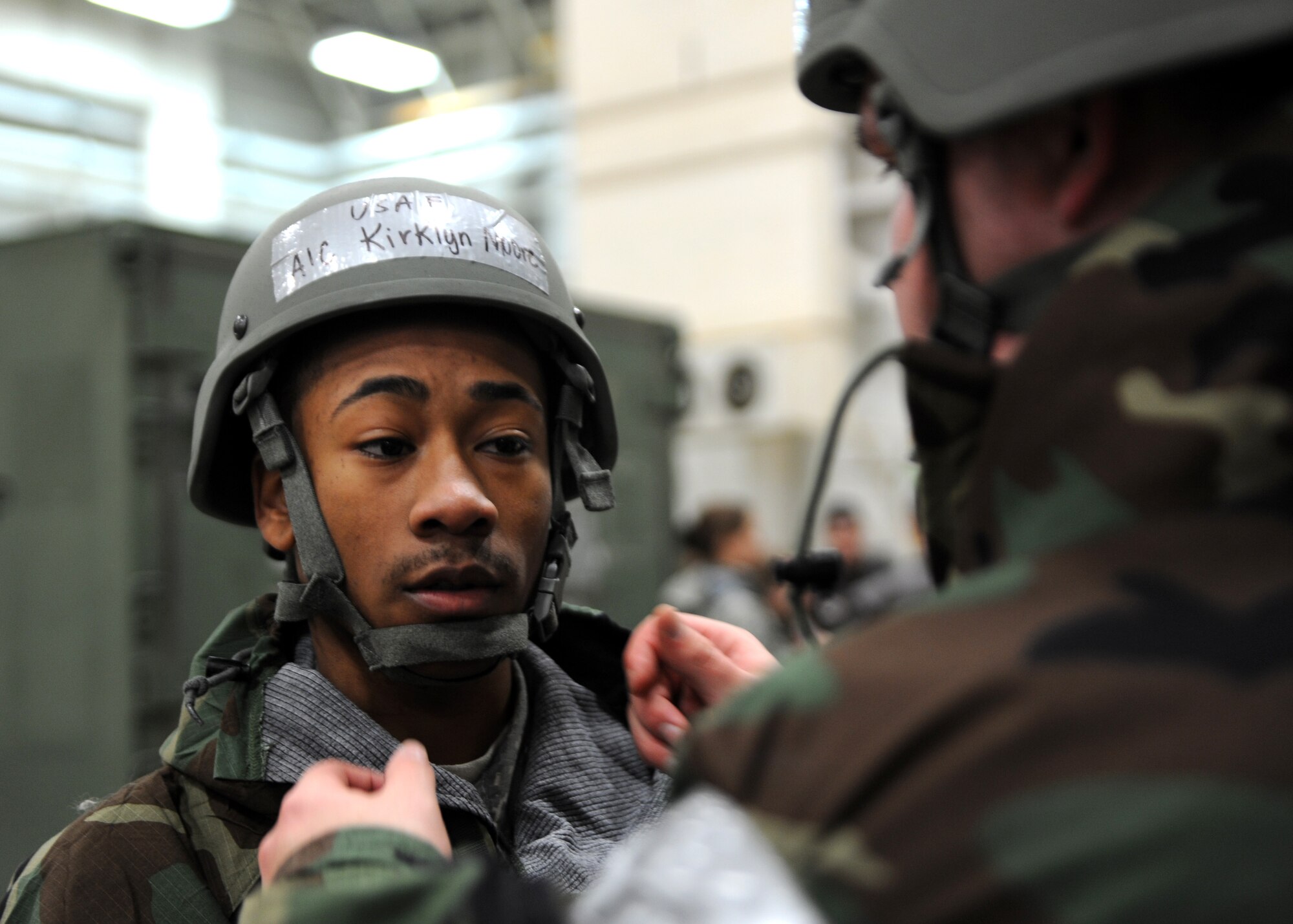 A male assists a male adjust a grey helmet.