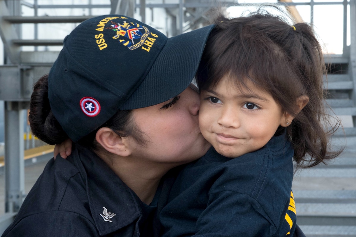 A sailor kisses a child on the cheek.