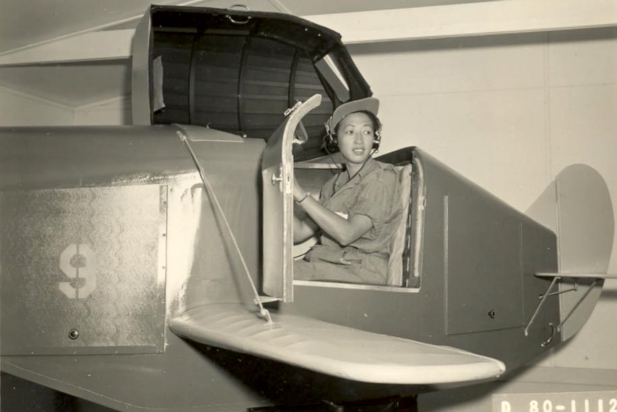 A historic photo of a member of the Women Airforce Service Pilots sits in an aircraft.