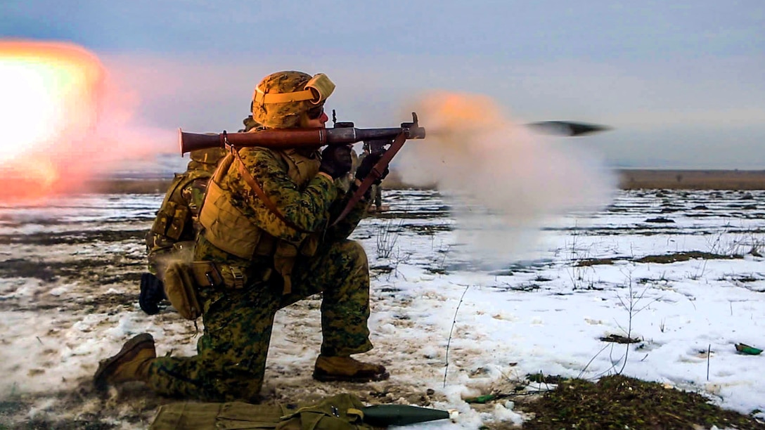 A Marine kneeling in a snowy field fires a rocket-propelled grenade launcher.