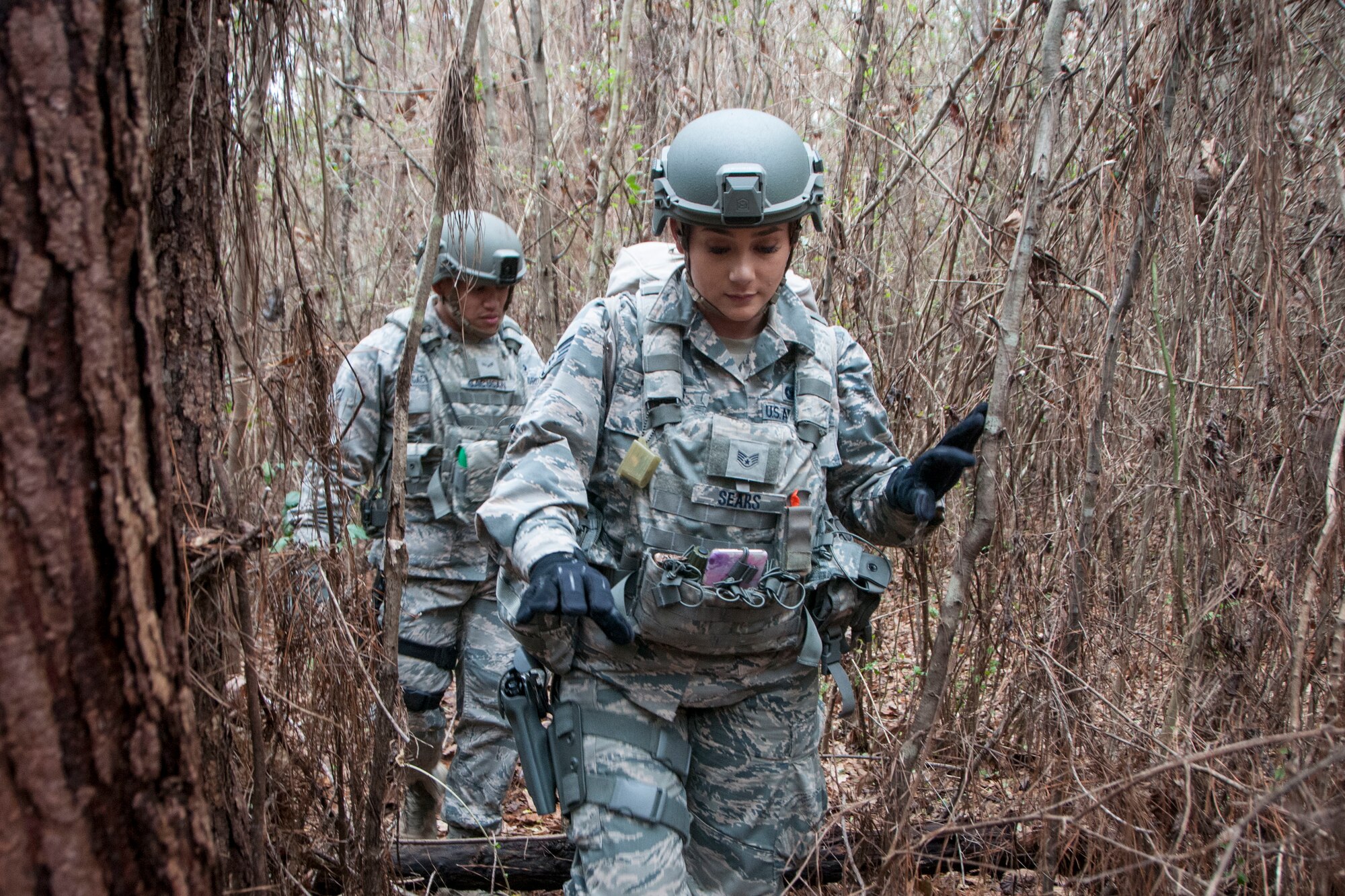 Staff Sgt. Sashalynn Sears (center) and Airman 1st Class Juanito Gacusan, 154th Security Forces Squadron fireteam member, searches the forest as part simulated search and rescue sweep as part of Patriot South Feb. 14, 2018, at Camp Shelby, Mississippi.