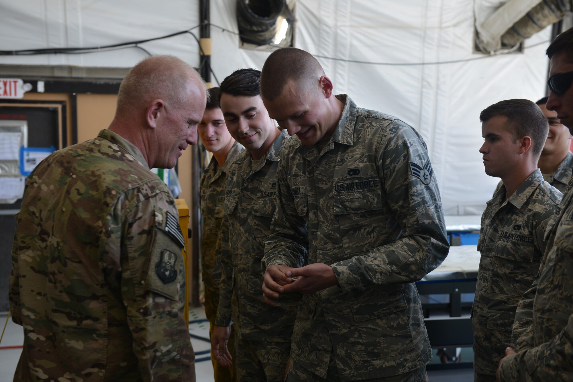 U.S. Air Force Airman 1st Class Anthony Gosnell shows Chief Master  Sgt. Frank Batten, command chief of Air Combat Command a coin he received from Gen. Mike Holmes, commander of Air Combat Command for being an
 outstanding performer Feb. 11, 2018, on Al Dhafra Air Base, United Arab  Emirates. Holmes visited Airman and talked with them about Air Force priorities and the importance of their role in the mission. 
 (U.S. Air Force photo by Tech. Sgt. Anthony Nelson J.R.)