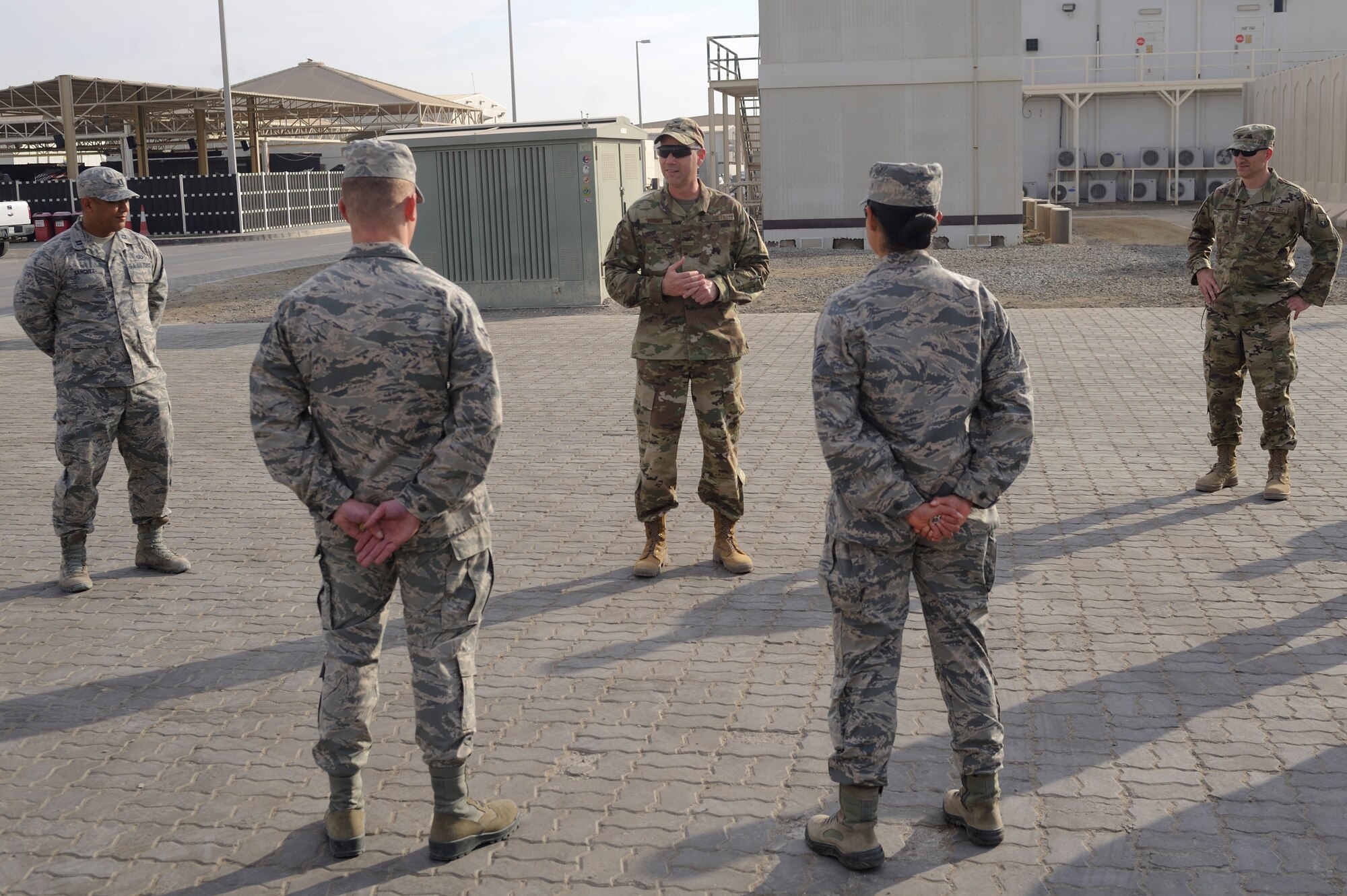 U.S. Air Force Col. Eric Rivera, U.S. Air Forces Central Command air reserve component advisor, coins two Airmen outside the 380th Air Expeditionary Wing headquarters building Al Dhafra Air Base, United Arab Emirates, Feb. 7, 2018. The origin of coining Airmen dates back to World War I, however nowadays they are used as mementos to recognize the outstanding performance and hard work of service members. (U.S. Air Force photo by Airman 1st Class D. Blake Browning)