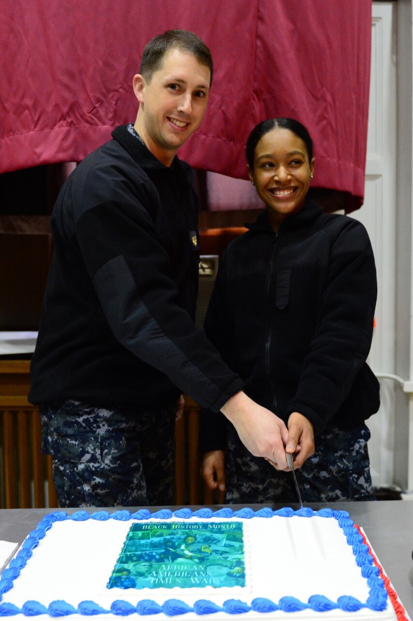 YOKOSUKA, Japan (Feb. 23, 2018) Lt. Cmdr. Tom Brewer and Culinary Specialist Seaman Recruit Daleyia Fisher, the youngest Sailor assigned to Commander, U.S. Seventh Fleet, cut the cake during the 2018 observance of National African American History Month at Commander, Fleet Activities Yokosuka Auditorium.