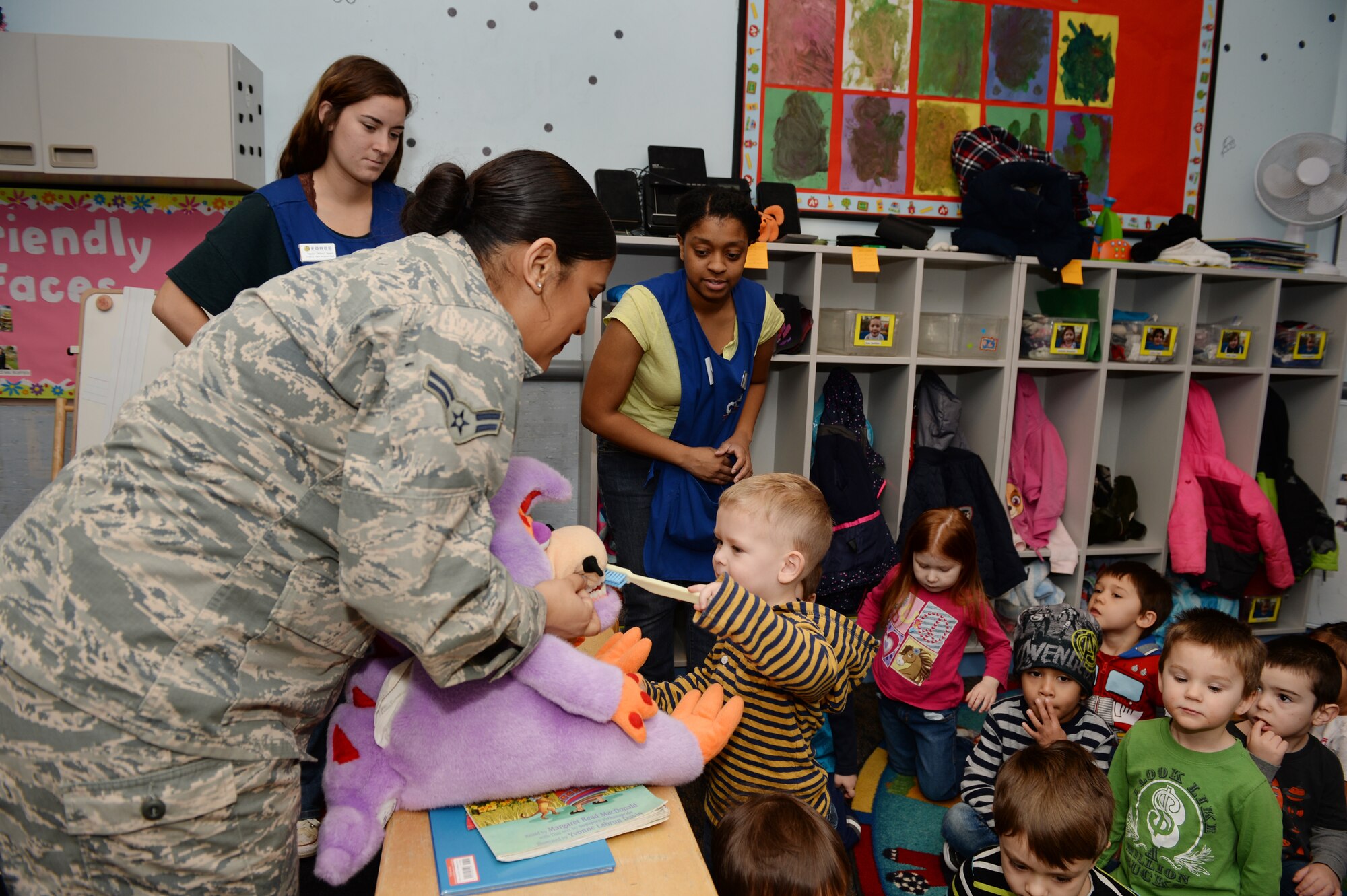 Airman 1st Class Tanisha T. Forbes, a dental technician assigned to the 48th Dental Squadron, holds a stuffed animal so a child may brush its teeth at the Child Development Center at Royal Air Force Lakenheath, England, Feb. 13, 2018. Forbes is a part of the dental health professional team tasked with promoting good oral hygiene in the Department of Defense schools and child care centers here. (U.S. Air Force photo/Airman 1st Class Shanice Williams-Jones)