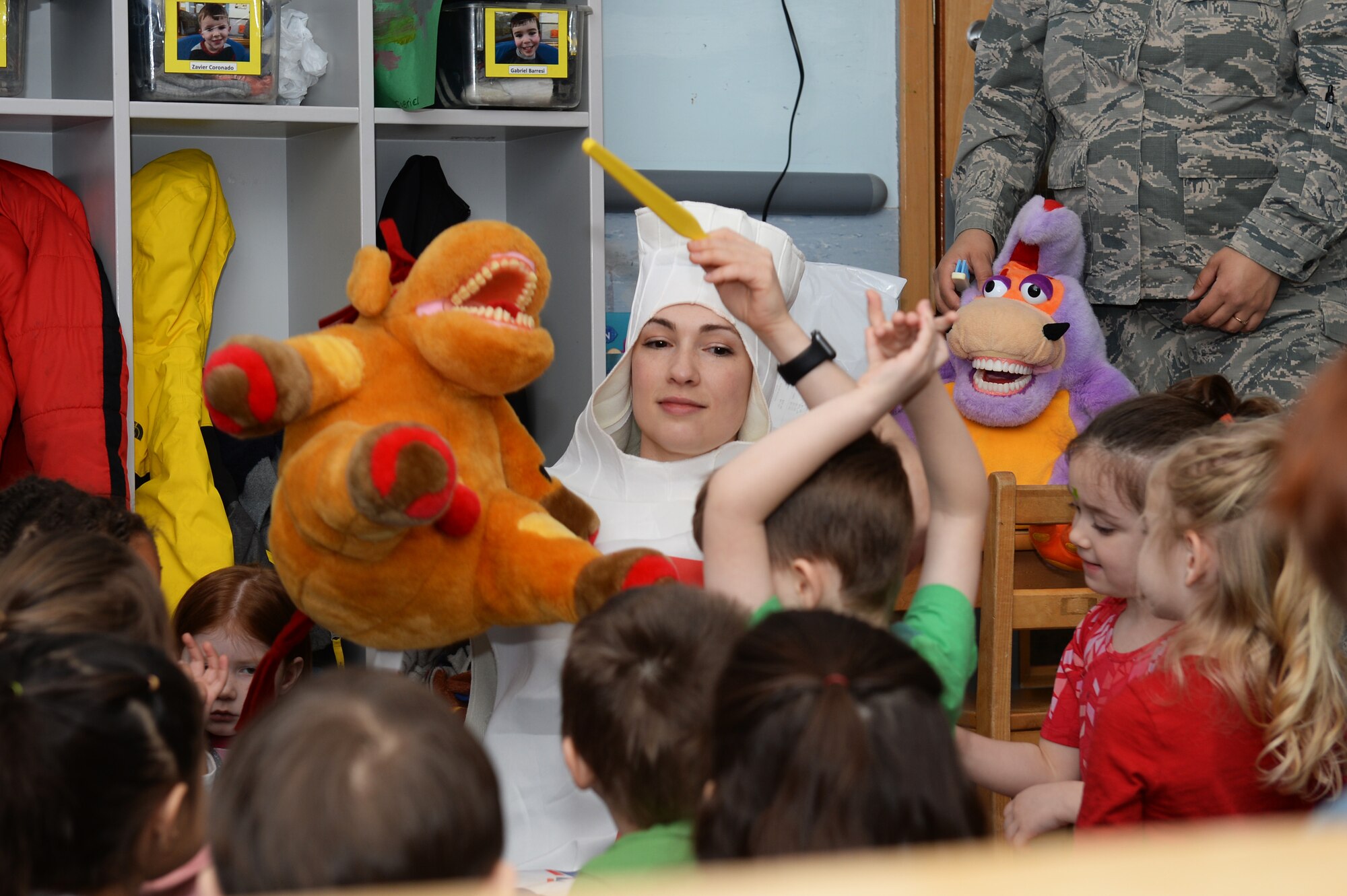 Capt. Candice V. Hodges, a general dentist assigned to the 48th Dental Squadron, raises a stuffed animal and toothbrush for children to see at the Child Development Center at Royal Air Force Lakenheath, England, Feb. 13, 2018. Hodges wore a toothpaste costume in the spirit of promoting good oral hygiene. (U.S. Air Force photo/Airman 1st Class Shanice Williams-Jones)