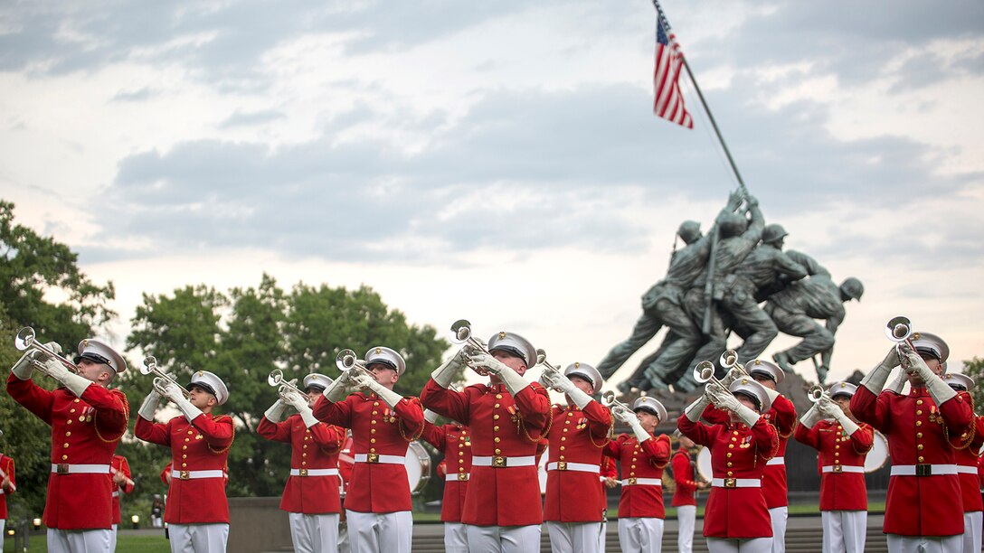 Marines play bugles in front of the Marine Corps War Memorial.
