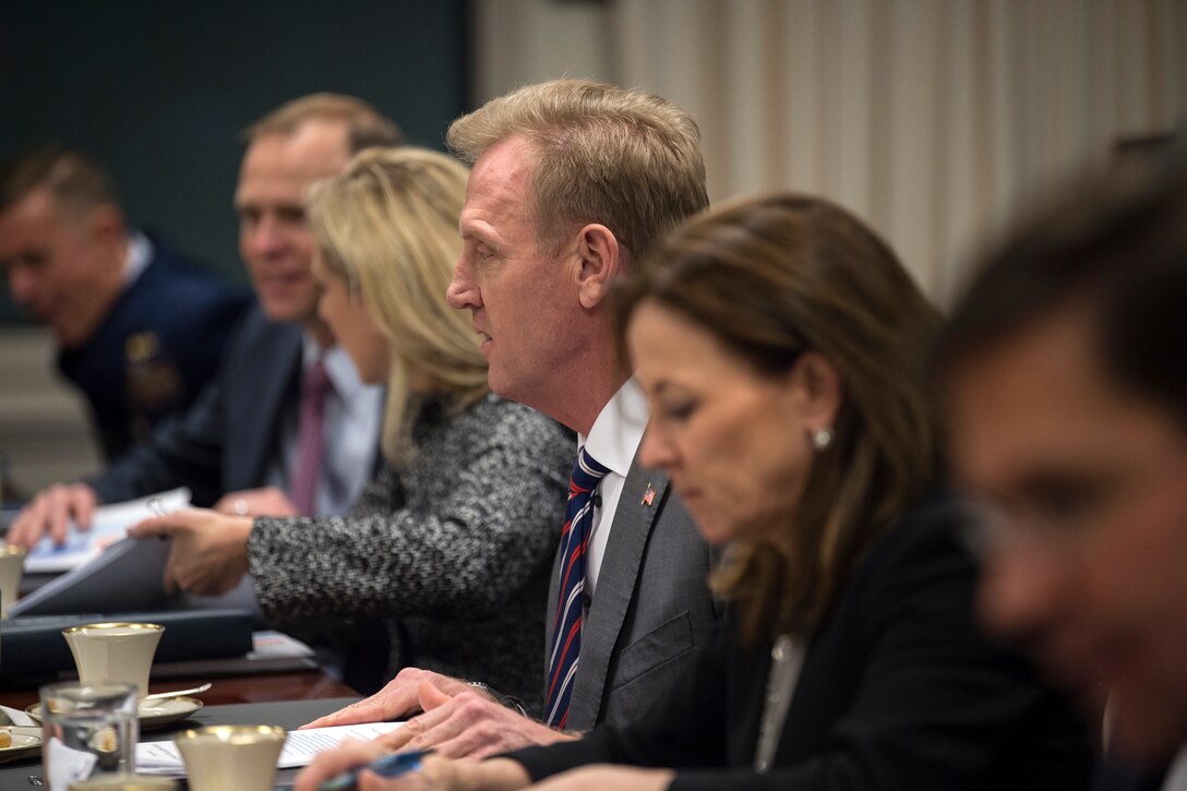 The deputy defense secretary sits at a table with other people.