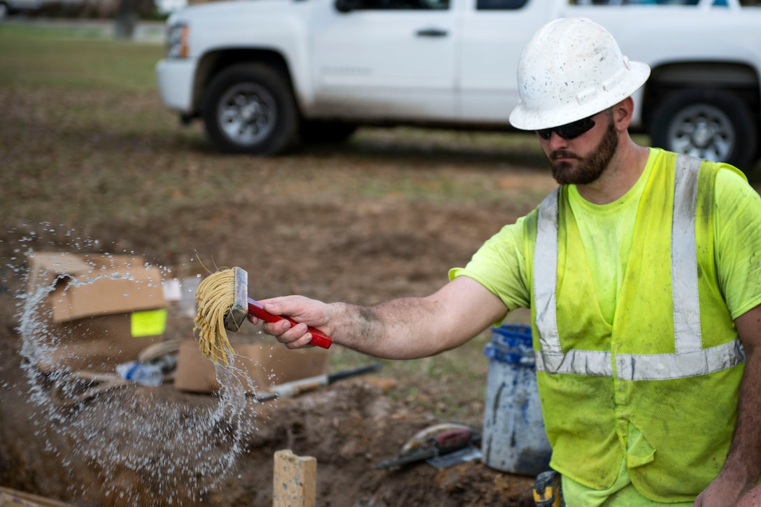 Kaiden Hall, construction laborer, wets cement during the reconstruction of Mitchell Gate, Feb. 21, 2018, at Moody Air Force Base, Ga. The 23d Civil Engineer Squadron partnered with civilian contractors to reconstruct the gate in an effort to improve the security posture with improved anti-terrorism force protection barriers. (U.S. Air Force photo by Airman 1st Class Erick Requadt)