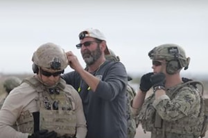 A man attaches a device to a service member's helmet.