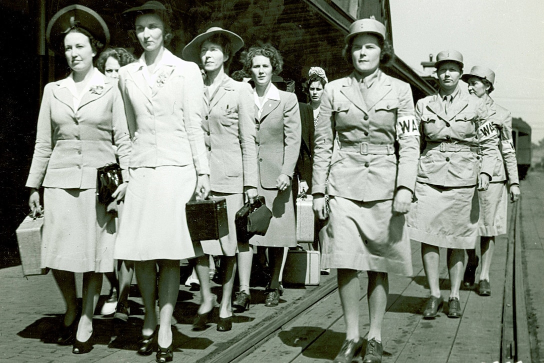 In a historic photo, Women's Army Auxiliary Corps members walk near railroad tracks.