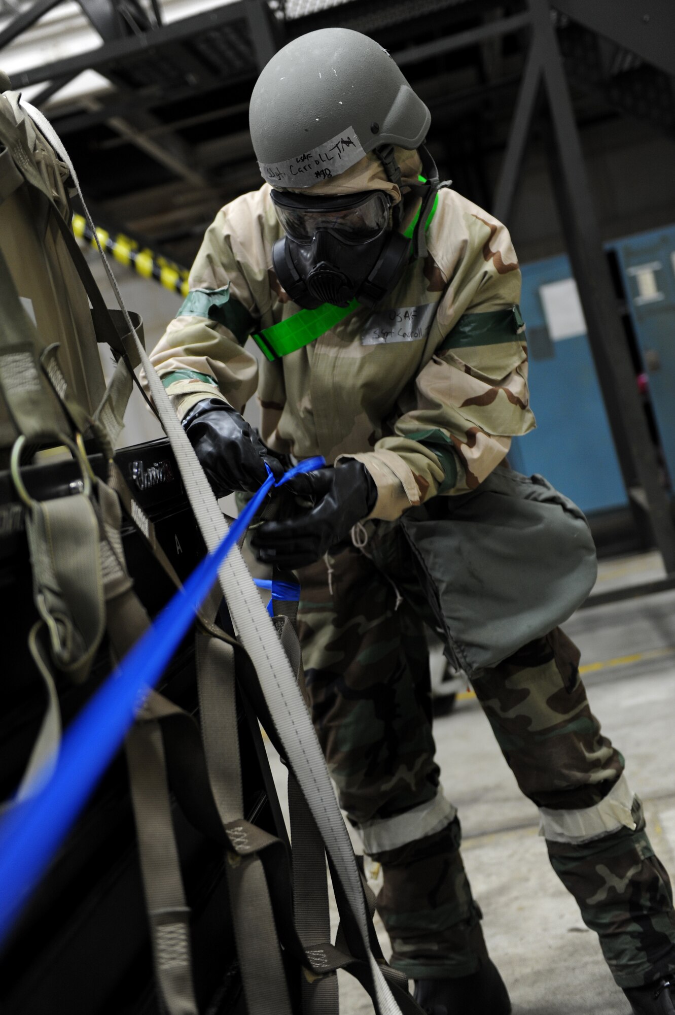 A male pulls a piece of blue tape over a pallet.