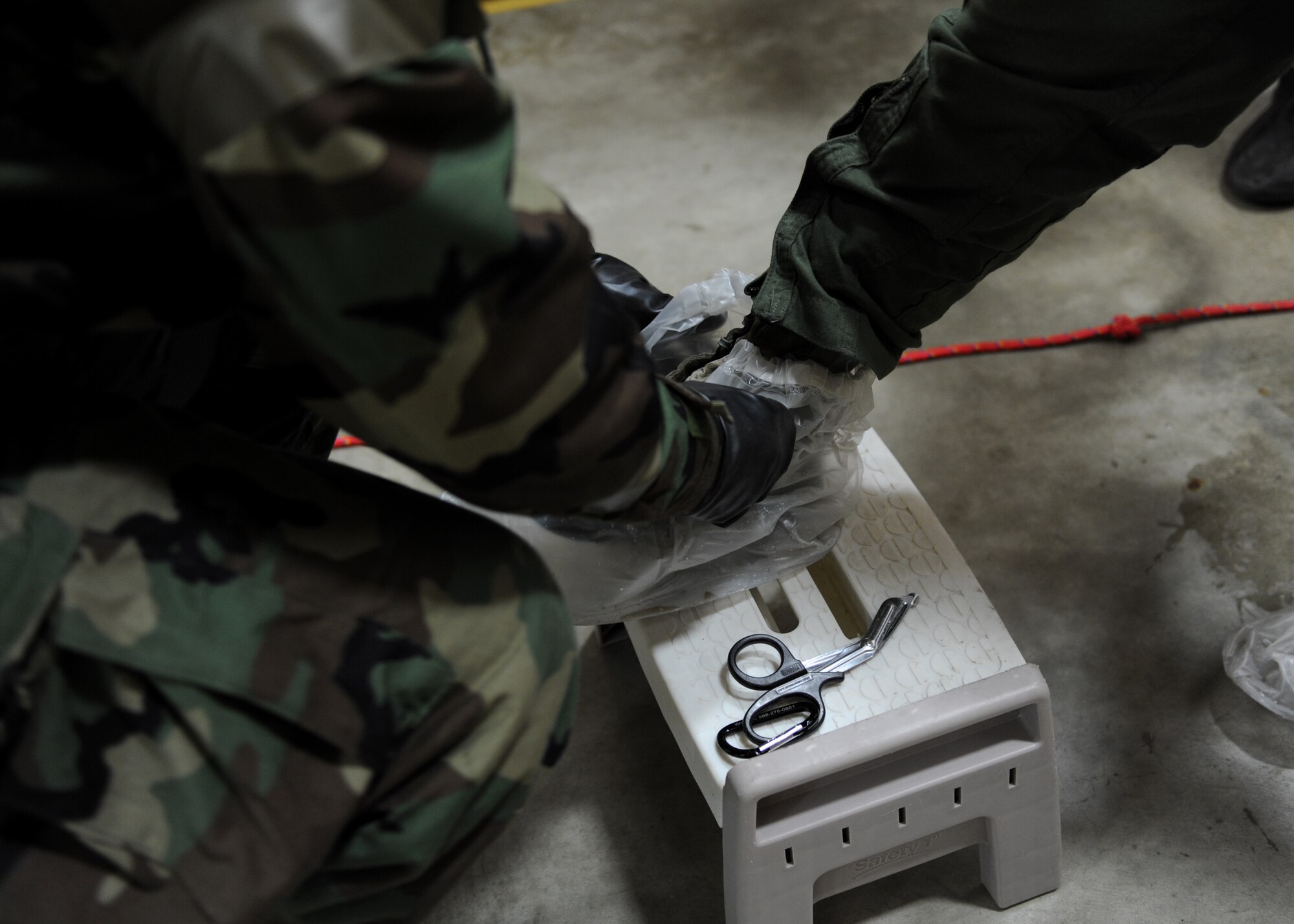 A photo with a male removing a clear plastic cover from a green combat boot.