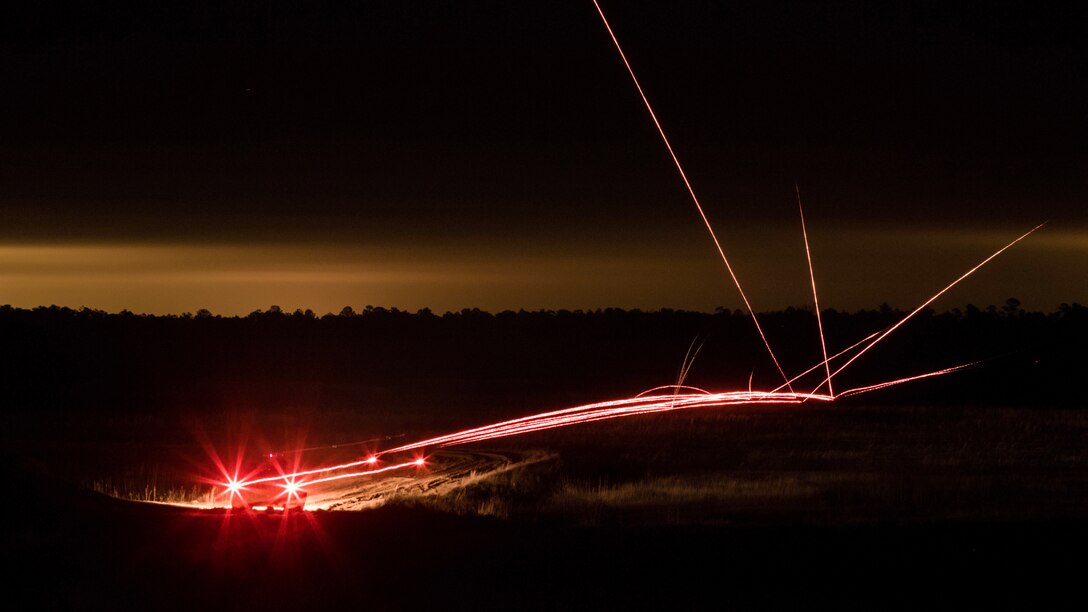Pinkish light beams shoot across a dark landscape.