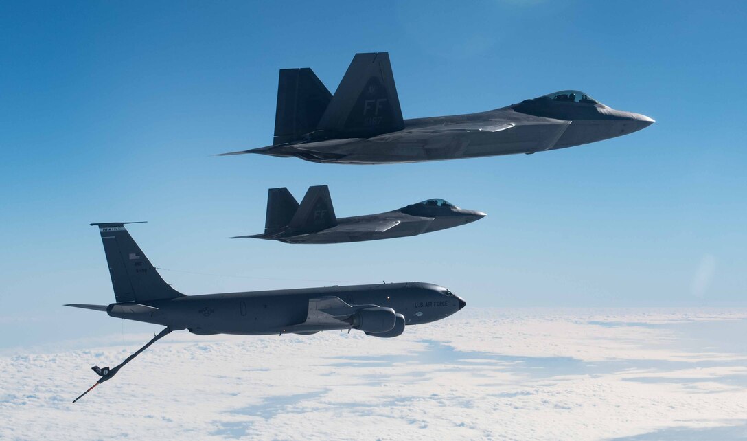 A KC-135 Stratotanker from the 101st Air Refueling Wing flies in formation with F-22 Raptors from the 94th Fighter Squadron over the Atlantic Ocean, February 22, 2018.