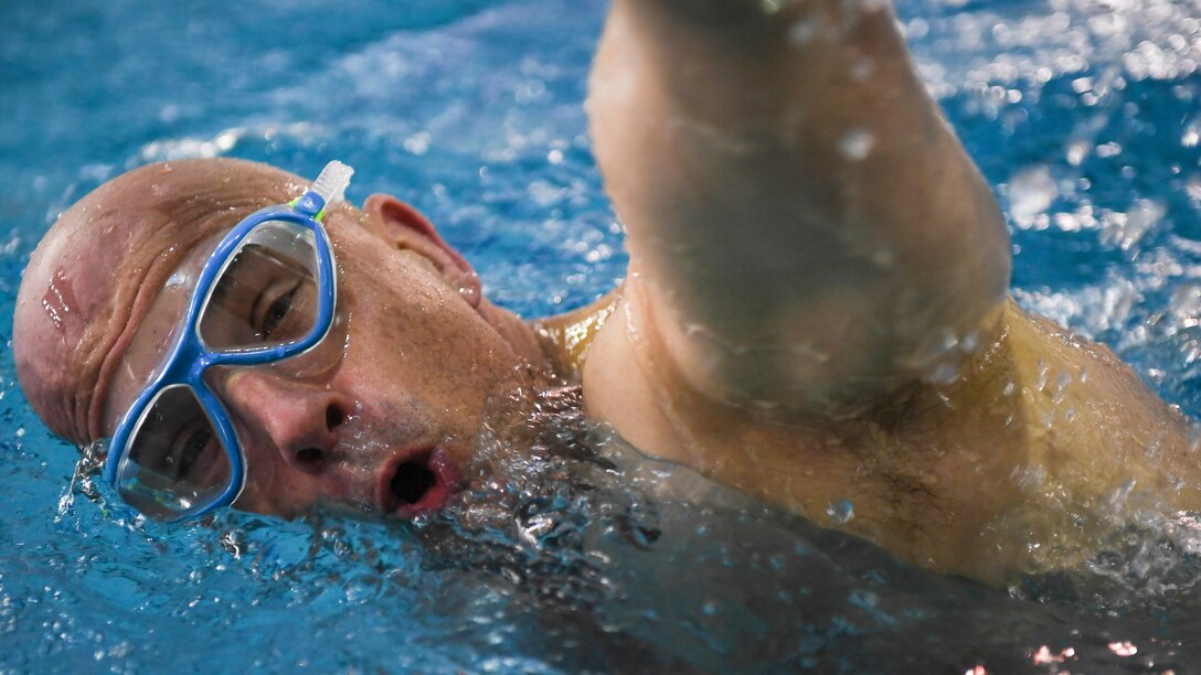 A swimmer wearing goggles takes a breath while swimming in a pool.