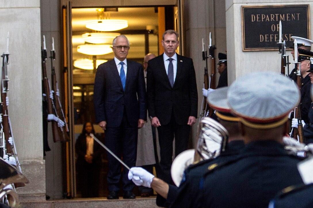 Two men stand at the top of the steps at the entrance to the Pentagon.