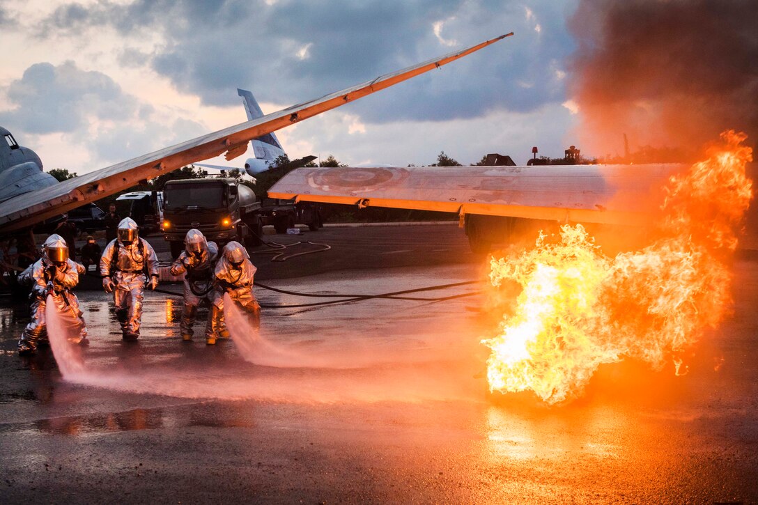 U.S. Marines and Thai navy firefighters work together to extinguish an aircraft fire simulating a crash during aircraft extraction training.