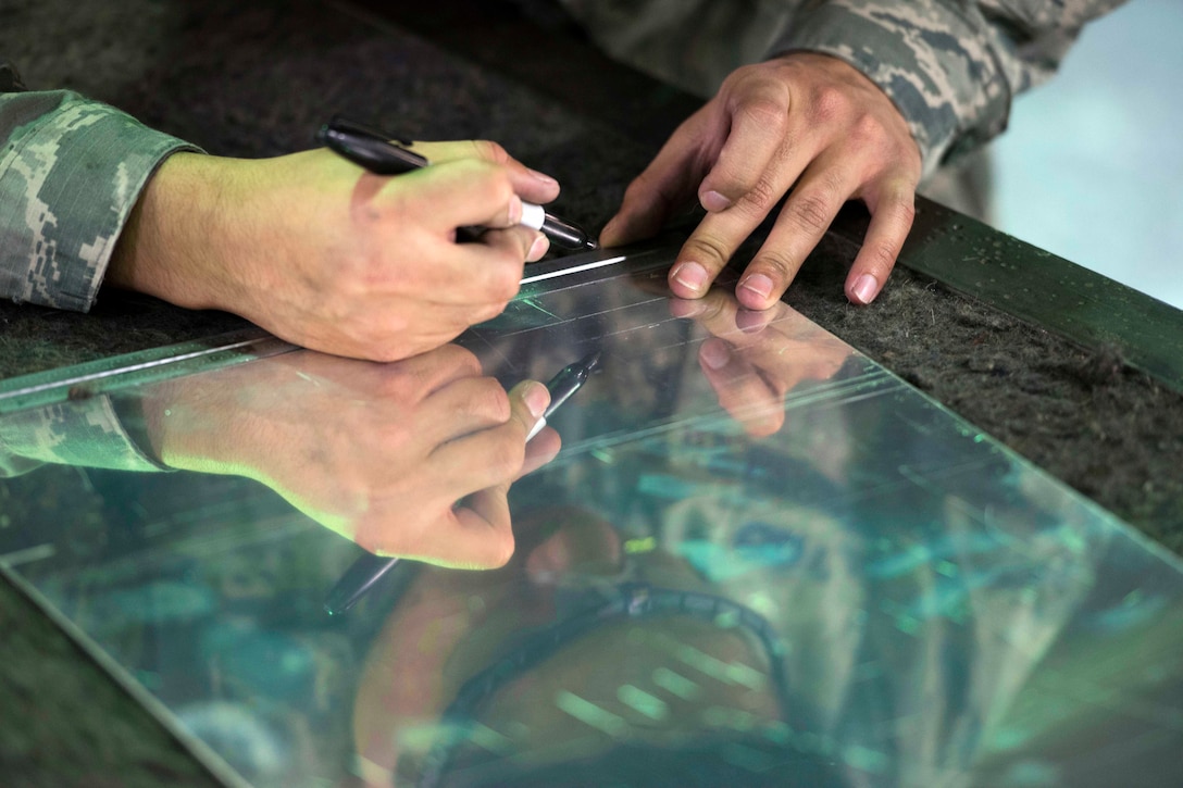 Air Force Airman Daniel Arellano marks sheet metal before cutting.