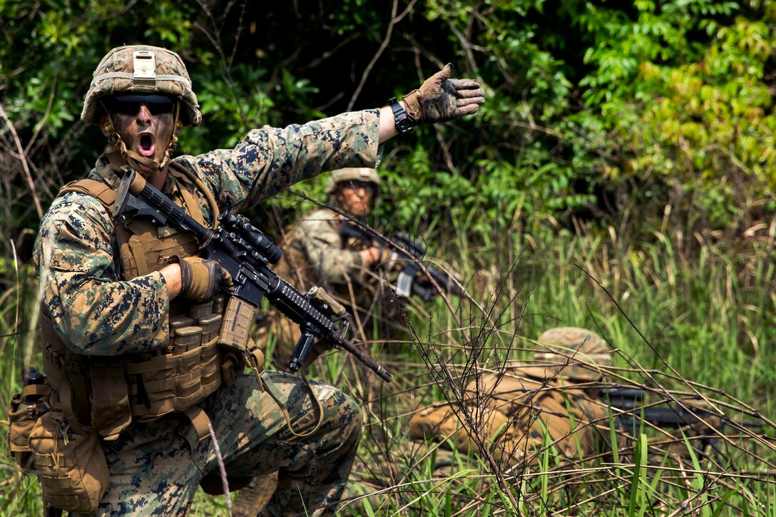 Marine Corps Cpl. Benton Allen yells out commands to his team members to move forward.