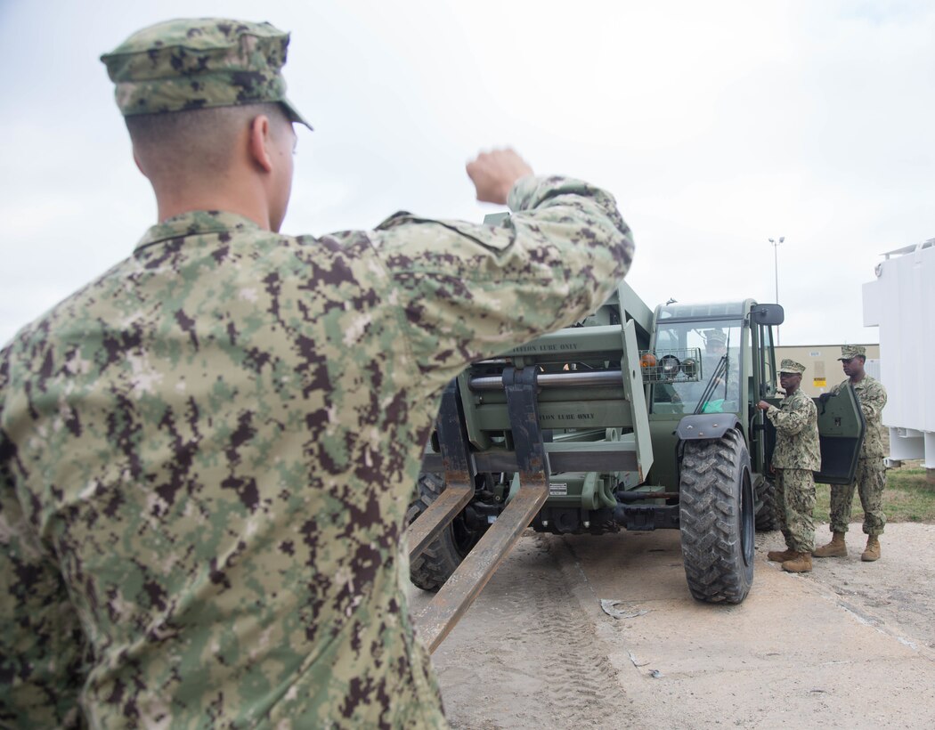 Troops operate an all-terrain forklift vehicle.