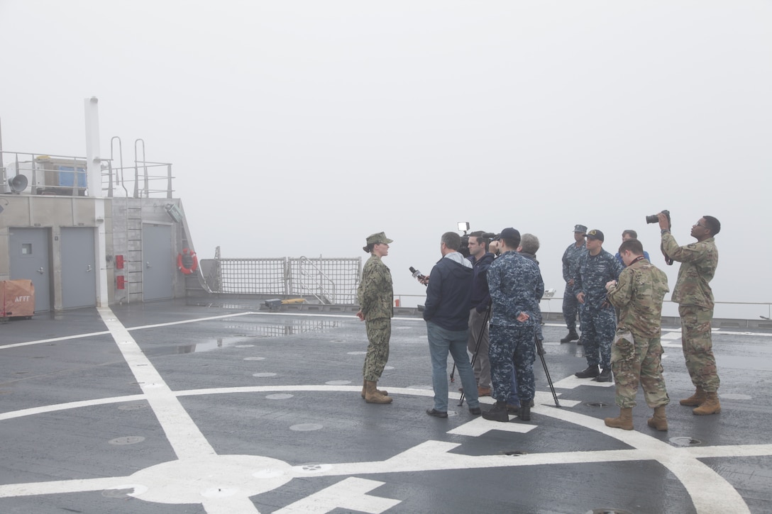 A military member gets interviewed by media aboard USNS Spearhead.