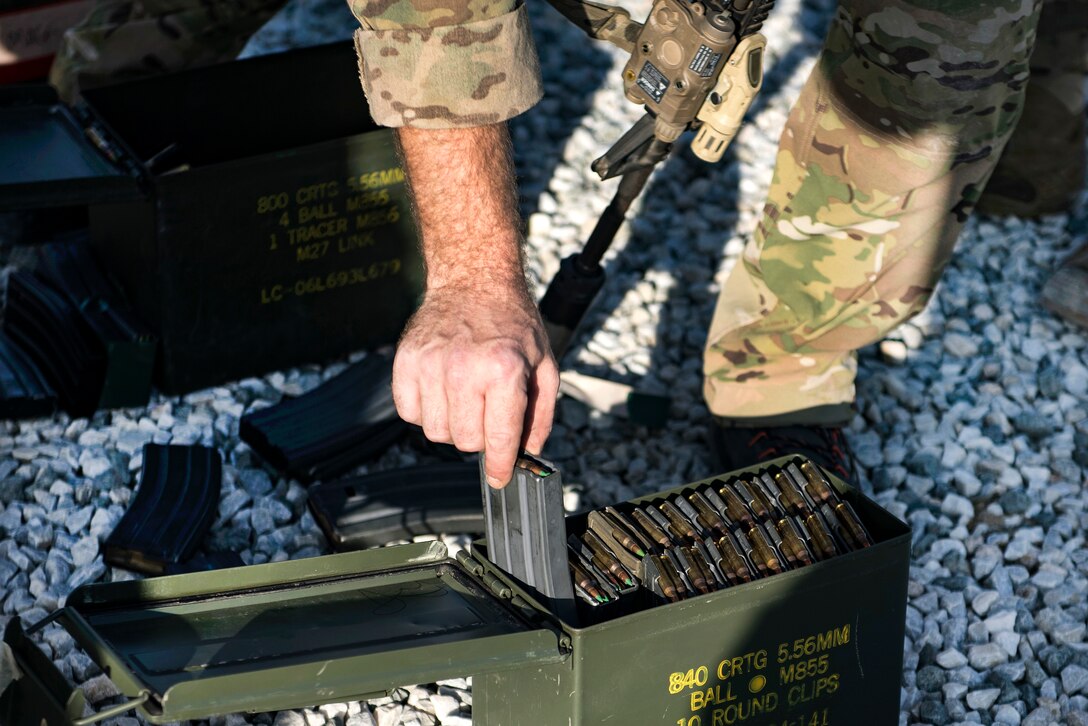 An Air Force pararescueman picks up a magazine loaded with 5.56 NATO ammunition before participating in weapons training.