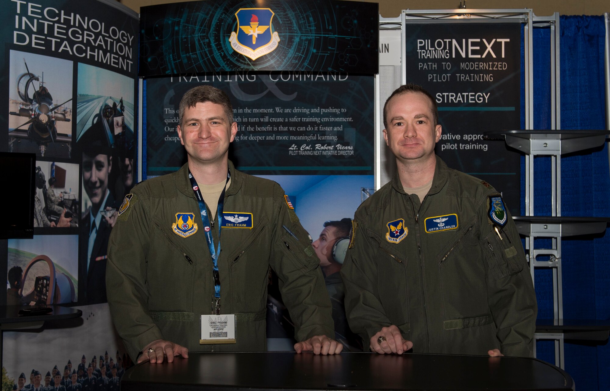 U.S. Air Force Lt. Col. Eric Frahm, and Maj. Justin Chandler, Pilot Training Next team members, man the Air Education and Training Command's Pilot Training Next booth at the 2018 Air Force Association Air Warfare Symposium in Orlando, Fla., Feb. 22, 2018. Pilot Training Next is a program to explore and potentially prototype a training environment that integrates various technologies to produce pilots in an accelerated, cost-efficient, learning-focused manner. (U.S. Air Force photo by Staff Sgt. Kenneth W. Norman)