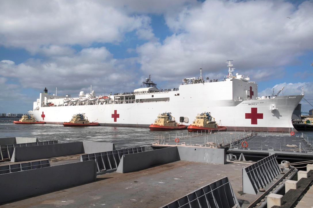 Several Tug boats help guide and move the Hospital ship USNS Mercy as it prepares to depart Naval Base San Diego.