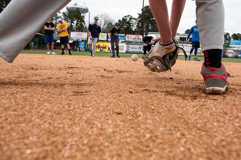Kids roll baseballs to each other as fielding practice during the kids' baseball clinic taught by coaches and players from the Air Force and Naval Academy baseball teams Feb. 24, 2018, at Grainger Stadium in Kinston, North Carolina. More than 30 boys and girls participated in the clinic, where they learned a variety of baseball skills to include, how to throw a baseball, how to field ground balls and line drives, and how to run the bases. (U.S. Air Force photo by Tech. Sgt. David W. Carbajal)