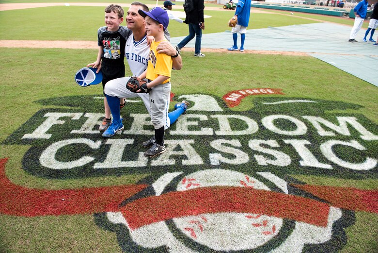 Mike Kazlausky, Air Force Academy baseball head coach, poses with kids for a photo after the kids' baseball clinic taught by coaches and players from the Air Force and Naval Academy baseball teams Feb. 24, 2018, at Grainger Stadium in Kinston, North Carolina. Kazlausky taught the kids how to present themselves during the national anthem and he taught the kids how to properly introduce themselves to people. (U.S. Air Force photo by Tech. Sgt. David W. Carbajal)