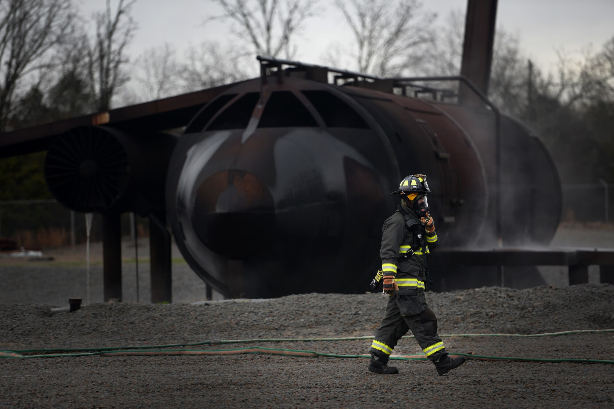 A firefighter walks in front of a simulated aircraft while wearing fire protection equipment.
