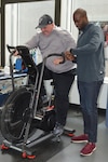 David Colbath completes a workout on an exercise bike Feb. 2, 2018 at the Center for the Intrepid at Joint Base San Antonio-Fort Sam Houston as physical therapist Oluwasegun Olomojobi times him. Colbath is one of eight people who were brought to Brooke Army Medical Center with multiple gunshot wounds inflicted by a lone gunman in Sutherland Springs, Texas on Nov. 5, 2017. He is currently rehabilitating from his injuries at the CFI.