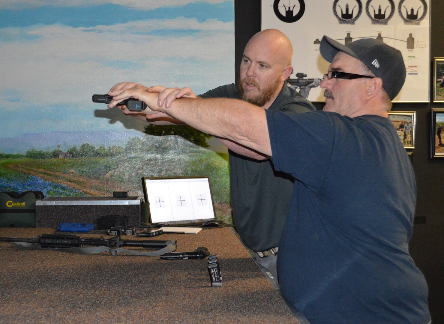 Scott Fitzgerald (left), Firearms Training Simulator instructor, works with David Colbath (right) on his hand positioning Feb. 15, 2018 at the Center for the Intrepid at Joint Base San Antonio-Fort Sam Houston. As part of his rehab at the CFI, Colbath, an avid hunter, is working with Fitzgerald to learn how to shoot left handed. Fitzgerald is helping Colbath with his hand/eye coordination and physical stance as he gets used to using his left hand as his dominant hand when shooting a gun.