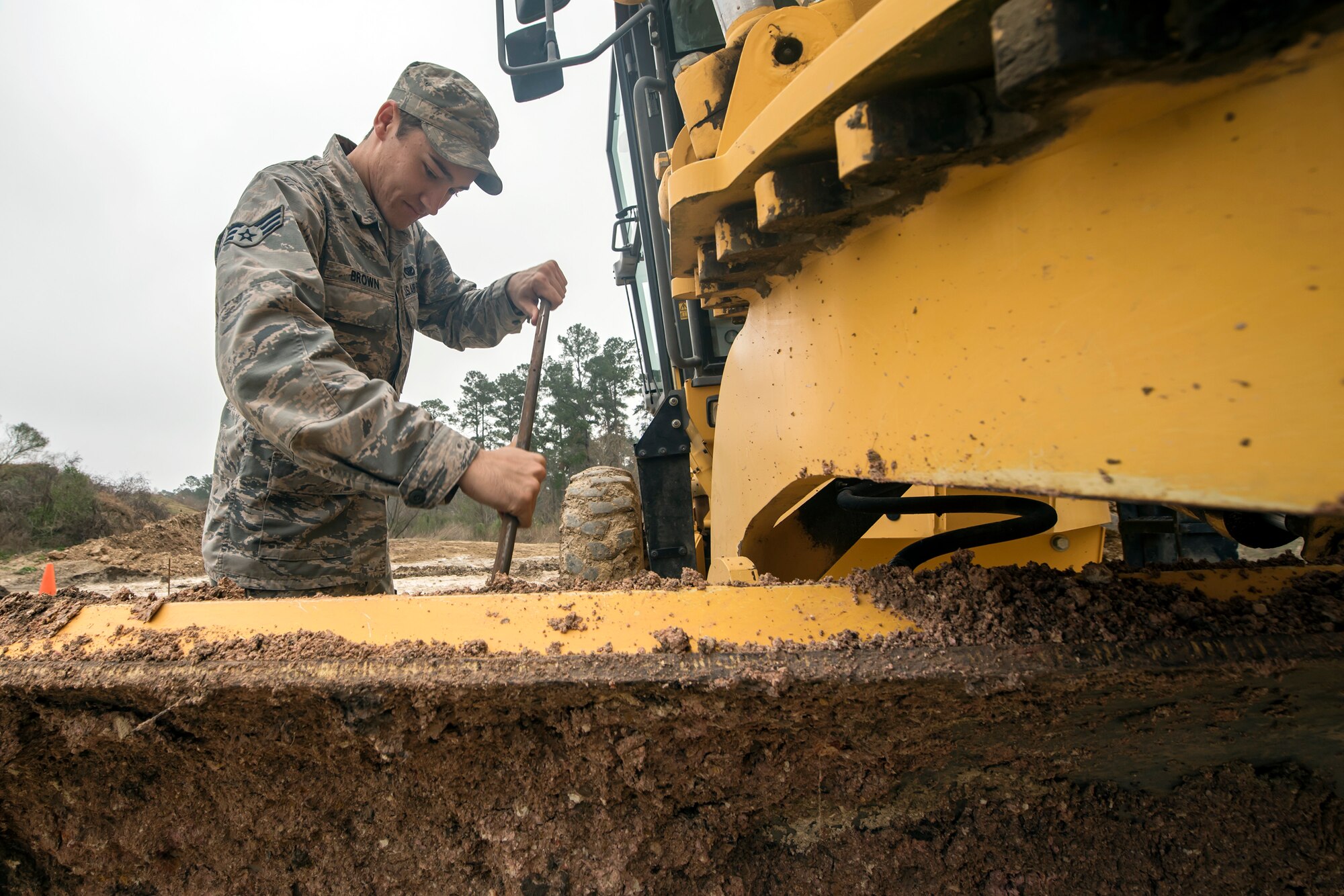 Senior Airman Davon Brown, 23d Civil Engineer Squadron pavements and equipment specialist, cleans dirt off the blade of a grader, Feb. 15, 2018, at Moody Air Force Base, Ga. Airmen from the 23d CES participated in a Prime Base Engineer Emergency Force training day to prepare for some of the wartime tasks they could encounter while in a deployed environment. (U.S. Air Force photo by Airman Eugene Oliver)