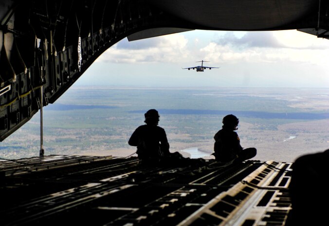 Master Sgt. Danny South, 16th Airlift Squadron loadmaster, left, sits at the edge of a C-17 Globemaster III with Airman 1st Class Elisha Toney, 16th AS loadmaster Feb. 24, 2018, over the coastline near Charleston, S.C.