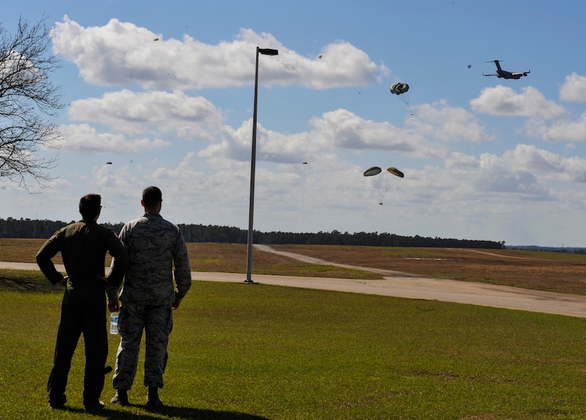Capt. Alex Hutcheson, left, 15th Airlift Squadron mission director, watches a high-velocity airdrop Feb. 24, 2018, at North Auxiliary Airfield, S.C.
