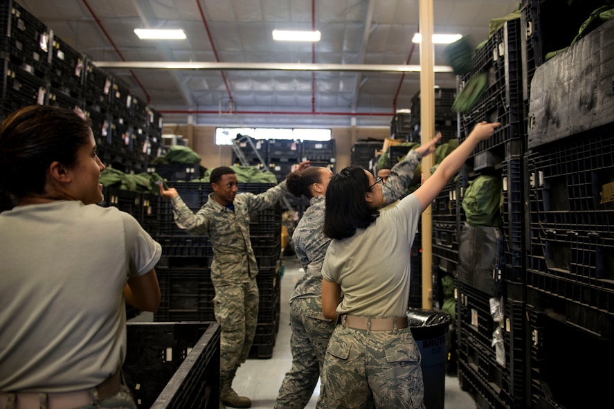 Airmen from the 23d Logistics Readiness Squadron (LRS) throw canteen covers into a bin in preparation for a Phase 1 exercise, Feb. 23, 2018, at Moody Air Force Base, Ga. The 23d LRS prepped approximately 400 A-bags, which consisted of items essential for deploying Airmen. This helped ensure the success of the Airmen participating in the exercise, which tested operations, maintenance and logistics to demonstrate the 23d Wing’s ability to rapidly deploy to meet the needs of combatant commanders. (U.S. Air Force photo by Airman 1st Class Erick Requadt)