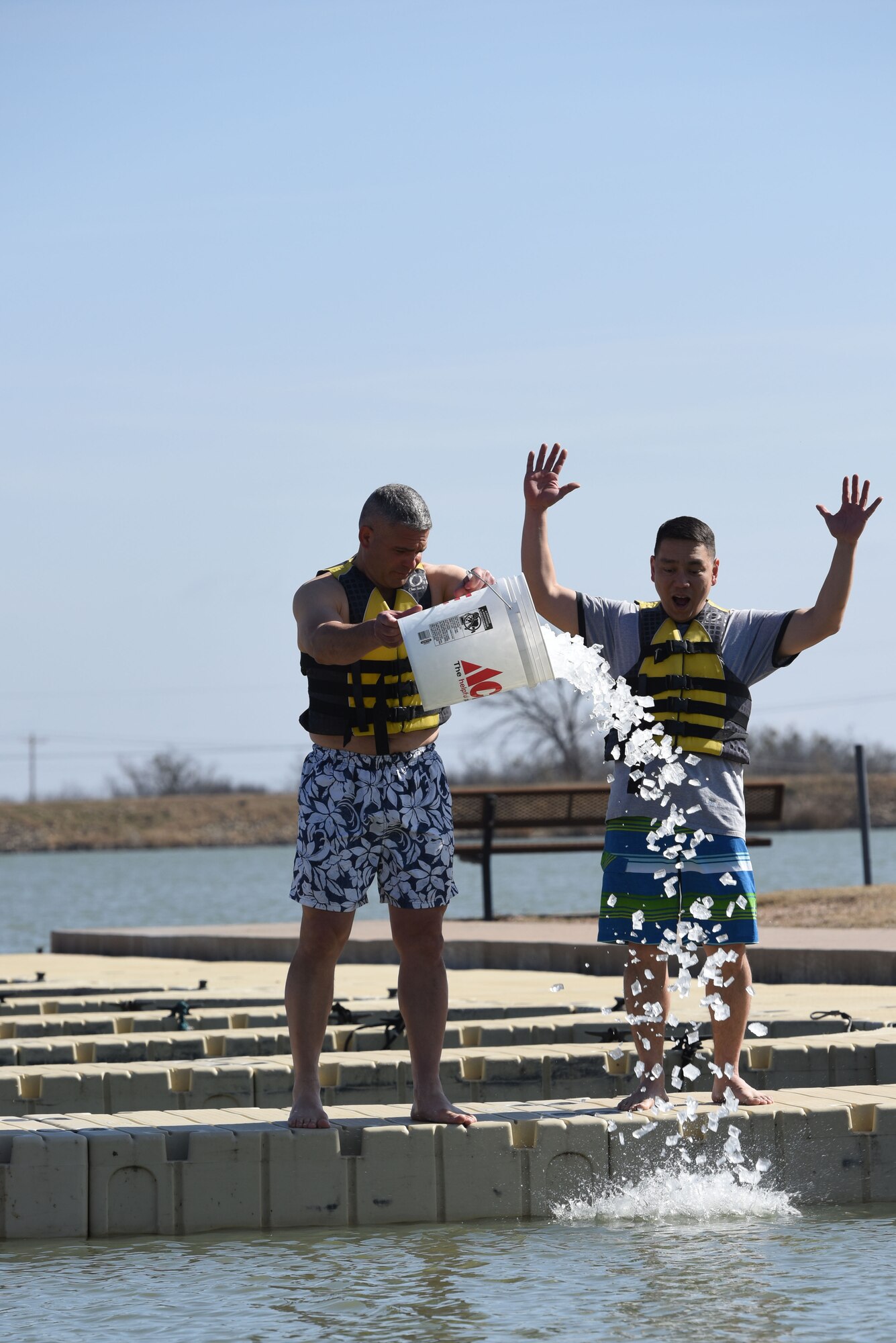 U.S. Air Force Col. Alex Ganster, 17th Training Group commander, and U.S. Army Lt. Col. Yukio Kuniyuki, 344th Military Intelligence Battalion commanding officer, pour ice into Lake Nasworthy to kick off the swim portion of the Polar Bear Plunge event hosted by the 17th Force Support Squadron in San Angelo, Texas, Feb. 24, 2018. Service members and their families had the opportunity to brave the water and compete for the coveted trophy of most participants from a unit. (U.S. Air Force photo by Airman 1st Class Seraiah Hines/Released)