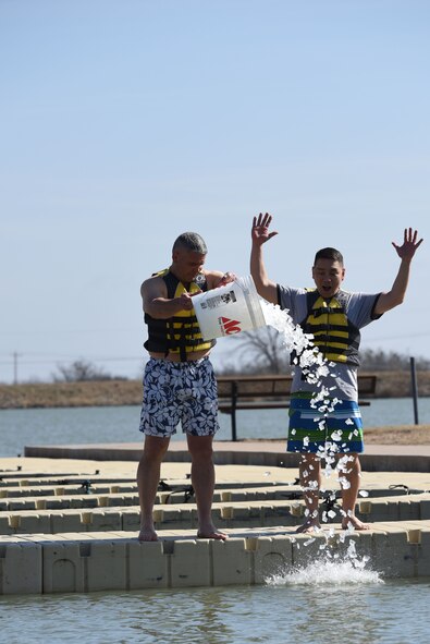 U.S. Air Force Col. Alex Ganster, 17th Training Group commander, and U.S. Army Lt. Col. Yukio Kuniyuki, 344th Military Intelligence Battalion commanding officer, pour ice into Lake Nasworthy to kick off the swim portion of the Polar Bear Plunge event hosted by the 17th Force Support Squadron in San Angelo, Texas, Feb. 24, 2018. Service members and their families had the opportunity to brave the water and compete for the coveted trophy of most participants from a unit. (U.S. Air Force photo by Airman 1st Class Seraiah Hines/Released)