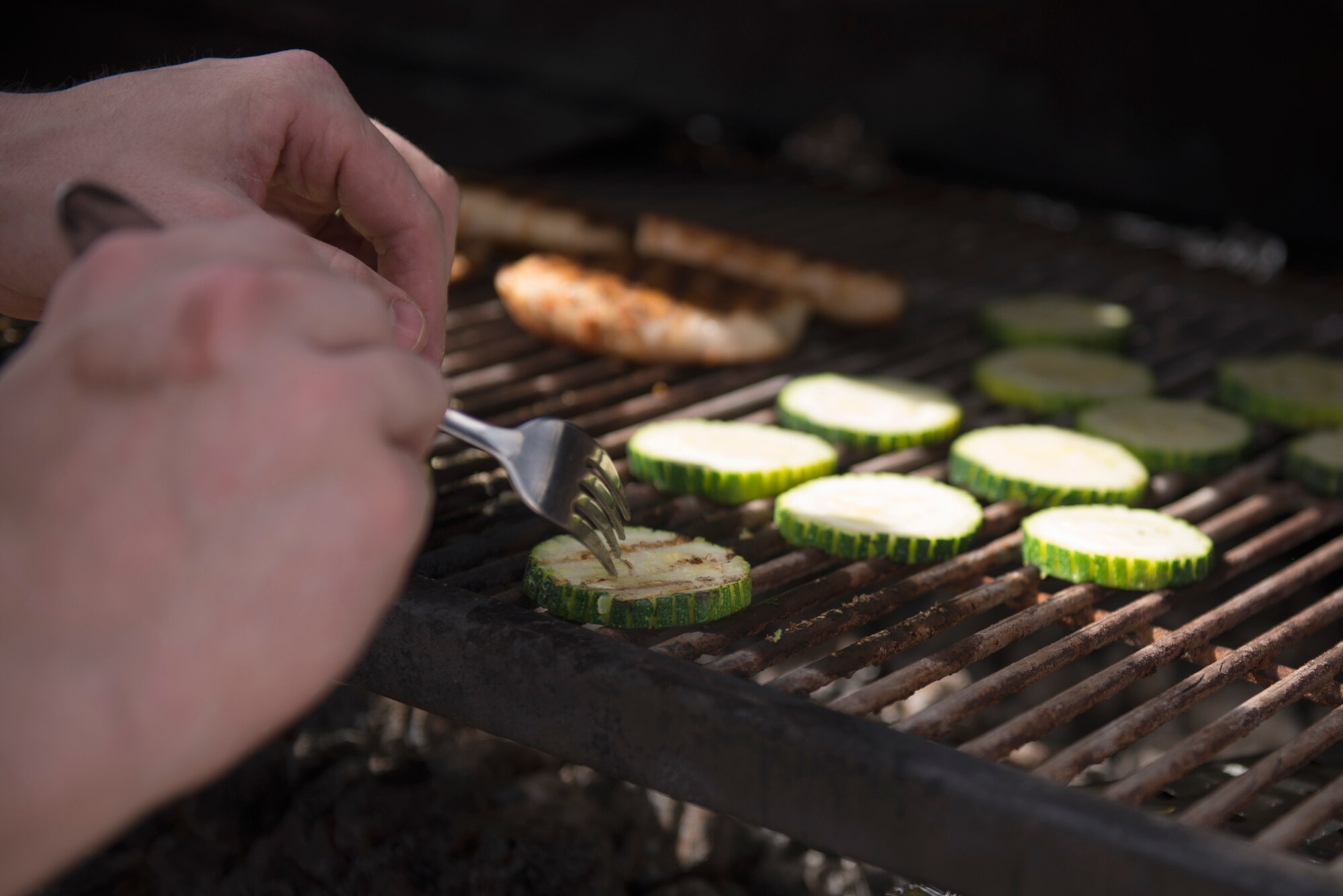 A competitor flips zucchini on the grill during the 2018 Grill Masters competition at Luke Air Force Base, Ariz., Feb. 23, 2018. The competition involved teams of two from across the base competing to grill the best meal. (U.S. Air Force photo/Senior Airman Ridge Shan)