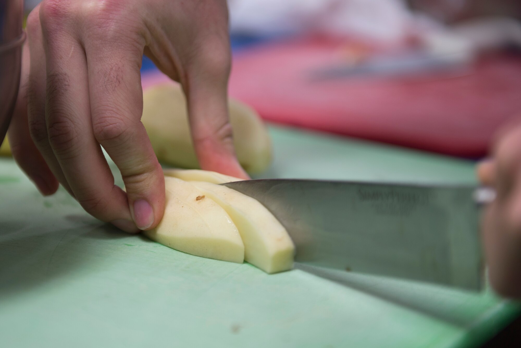 A competitor of the 2018 Grill Master competition at Luke Air Force Base, Ariz., slices a potato Feb. 23, 2018. Competitors, forming teams of two, cooked a meal for three judges who tasted and graded their finished product based on presentation, flavor and creativity. (U.S. Air Force photo/Senior Airman Ridge Shan)