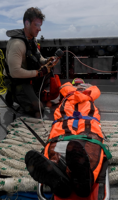 Naval Air Crewman (Helicopter) 2nd Class Spencer Kachele, assigned to the “Island Knights” of Helicopter Sea Combat Squadron (HSC) 25, secures a litter, loaded with a search and rescue (SAR) dummy, aboard a Mark VI patrol boat manned by Coastal Riverine Squadron 4, Det. Guam, during a joint SAR exercise with U.S. Coast Guard Sector Guam, Feb. 23, 2018.