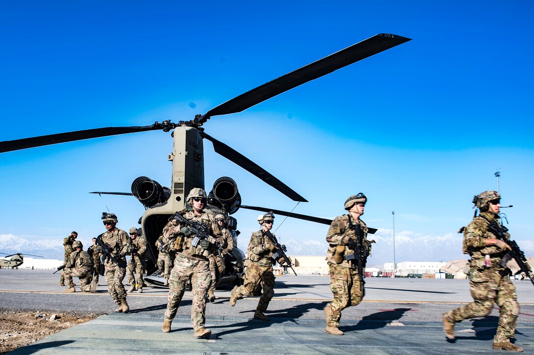 Soldiers rush out of a CH-47 Chinook helicopter onto the flightline before conducting integration and medical training with airmen.