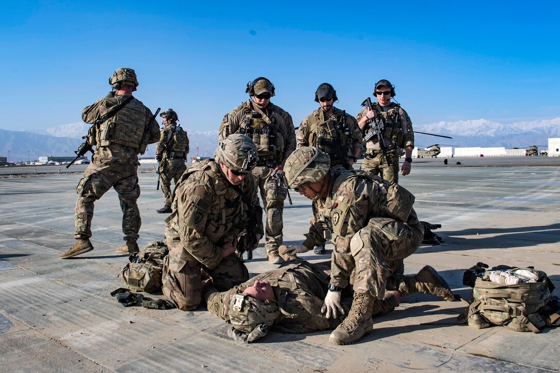 Air Force pararescuemen observe soldiers providing medical aid to a simulated casualty.