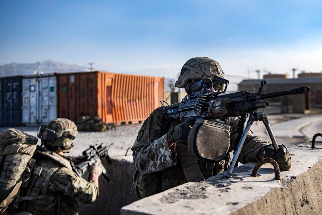 Soldiers set up a perimeter security behind concrete barriers during a training exercise.