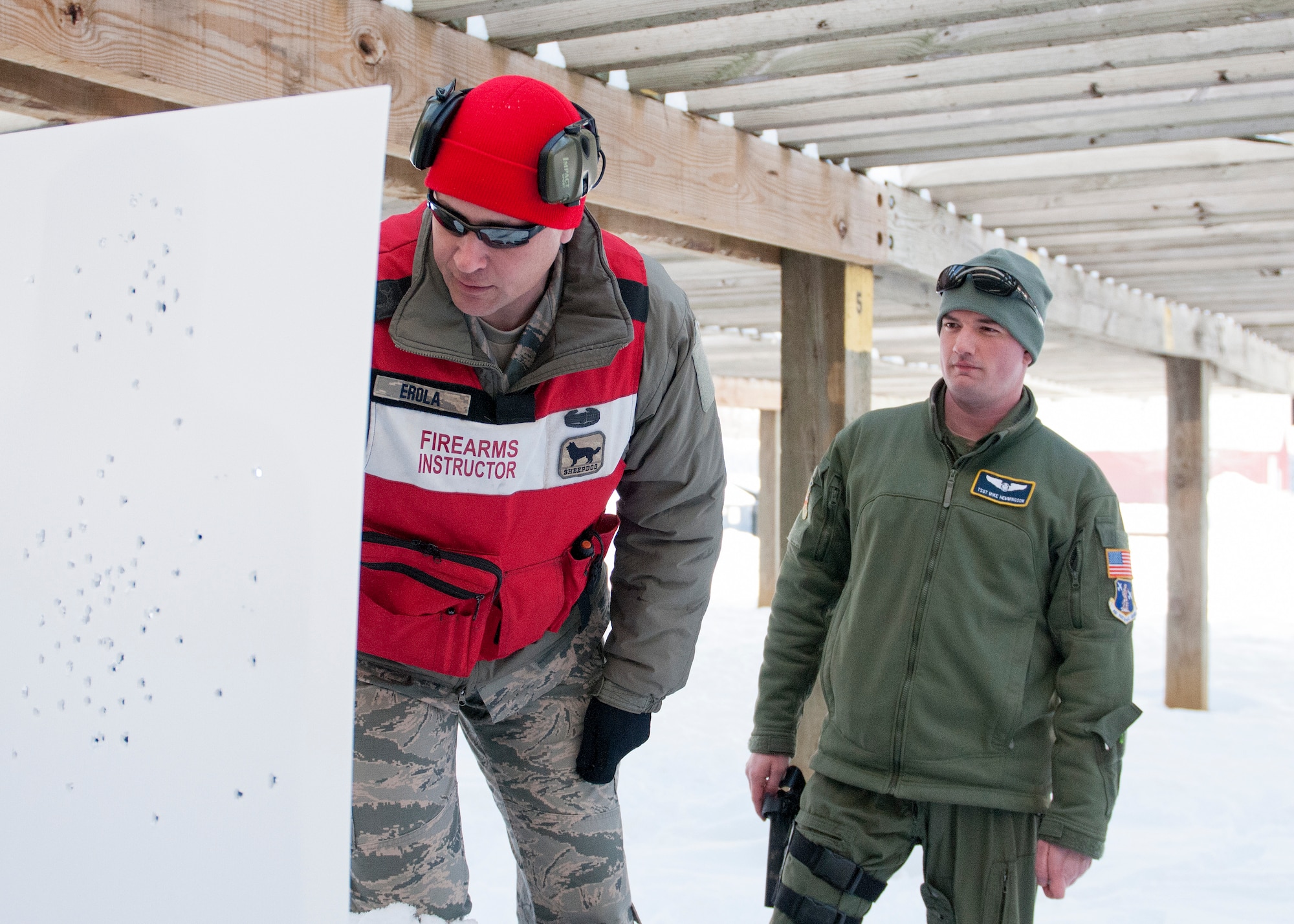 U.S. Air Force Tech. Sgt. Brian Erola, left, a combat arms training and maintenance instructor with the 133rd Security Forces Squadron, counts the puncture holes on the target after the completion of a M9 Beretta pistol weapons qualification course in Coon Rapids, Minn., Feb. 23, 2018.