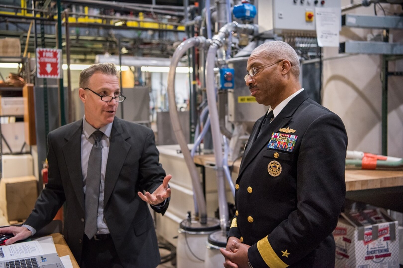 Rear Adm. Jesse Wilson, commander, Naval Surface Force Atlantic, listens to Bill Hertel, a mechanical engineer with the Solid Waste, Pollution Prevention and Hazardous Material Management Branch, on Feb. 13, 2018, as he describes the Mobile Cleaning, Recovery and Recycling System that is used onboard ships for flight deck cleaning. During Wilson's visit to Naval Surface Warfare Center, Carderock Division in West Bethesda, Md., he was a guest speaker for the Black History Month celebration.