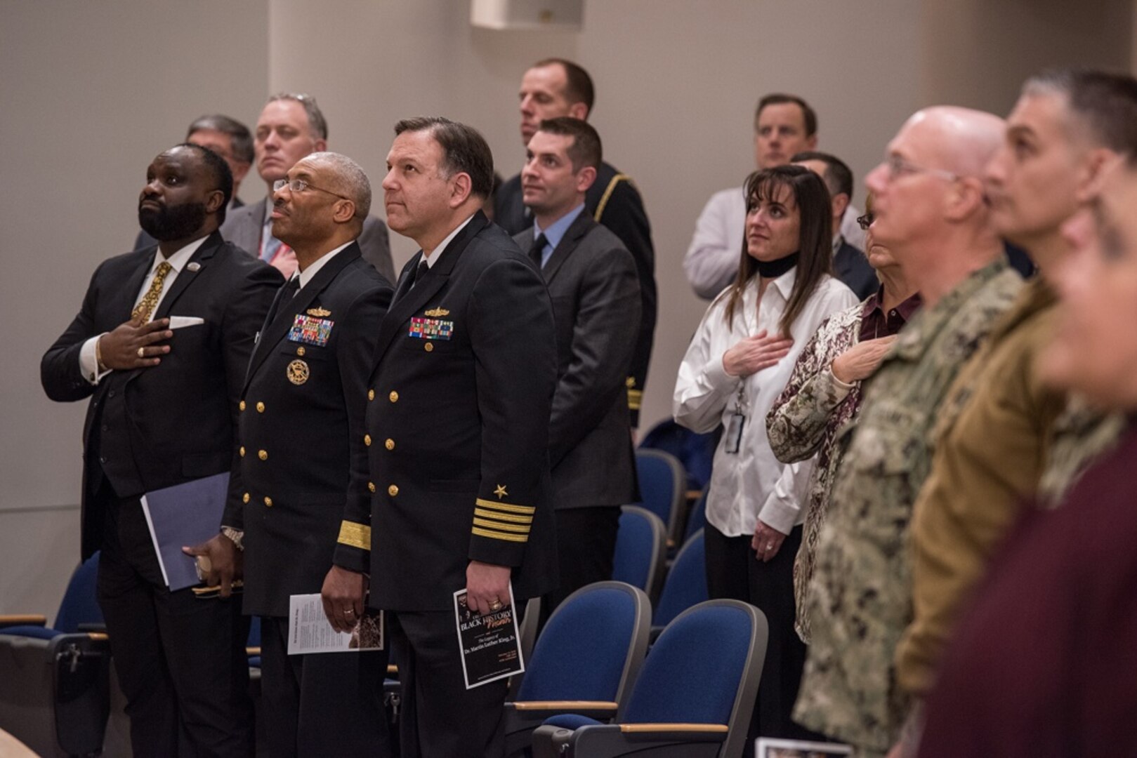 Duane Williams (left), SES, director of operations with the Department of Agriculture; Rear Adm. Jesse Wilson, commander, Naval Surface Force Atlantic; and Capt. Mark Vandroff, commanding officer, Naval Surface Warfare Center, Carderock Division, give honors as the National Anthem is played at the beginning of Carderock's Black History Month celebration Feb. 13, 2018, in West Bethesda, Md.